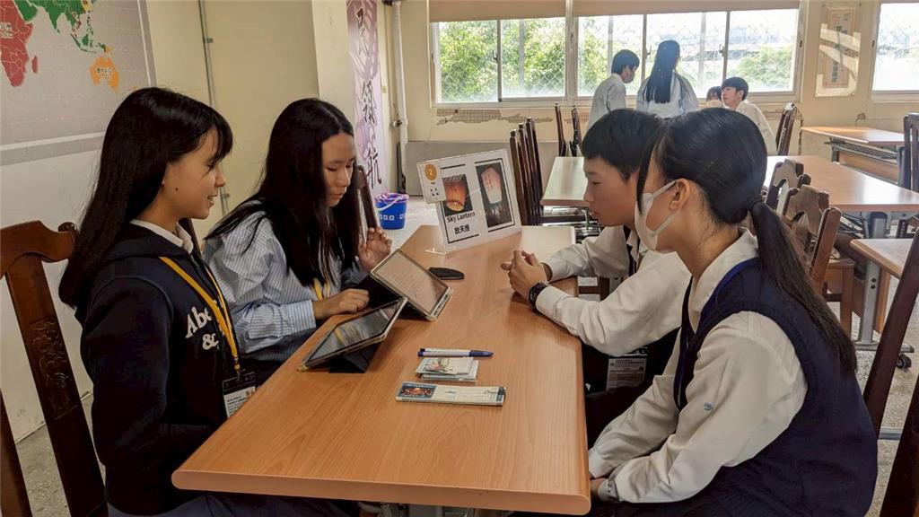 教育園丁的話圖片三民學生以英語介紹放天燈的由來，並準備英、日雙語電子簡報，協助日本學生理解內容；桌上另備有許願用的天燈造型便利貼及紀念機票書籤，增添活動體驗與紀念價值。
